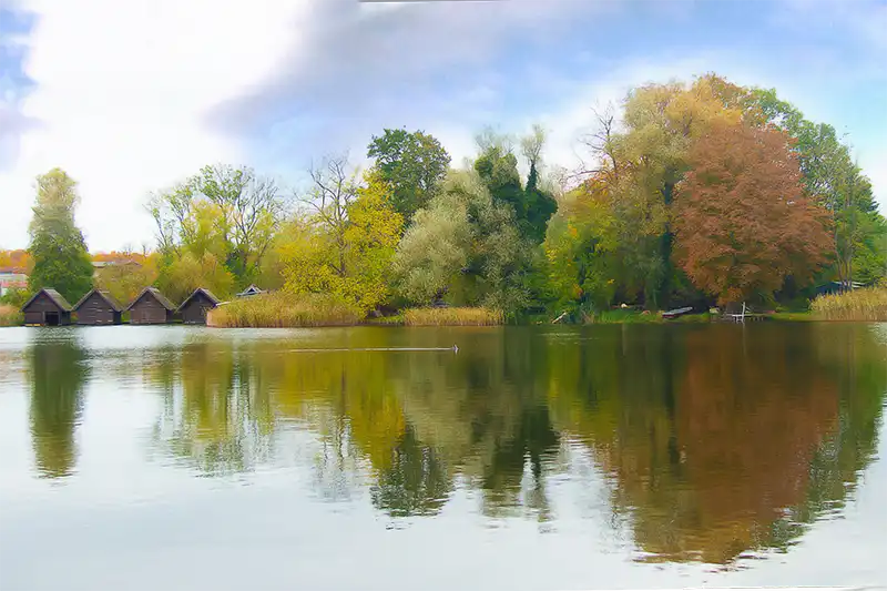 Blick über den Klostersee in Dargun mit Bootshäusern und idyllischer Uferlandschaft in Mecklenburg-Vorpommern.