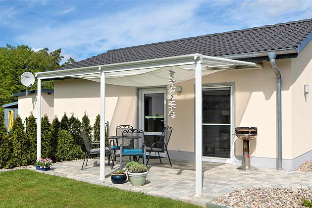 Überdachte Terrasse des hundefreundlichen Ferienhauses Paula am Klostersee in Dargun mit Sitzgruppe und Grill.